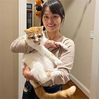 A person standing in a hallway holding an orange-and-white cat
