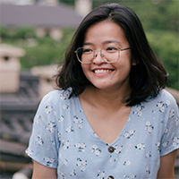 A person wearing glasses and a blue top with white flowers