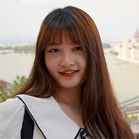 A person with long hair wearing a white blouse with black trim