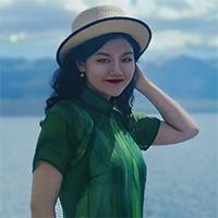 A person in a multihued green shirt with a black-trimmed straw hat