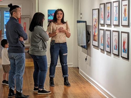 artist Venazir Martinez speaks with visitors attending an exhibition of her work in an art gallery at Duke