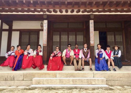 Students sitting on the steps of a traditional Korean house wearing hanbok (Korean clothing)