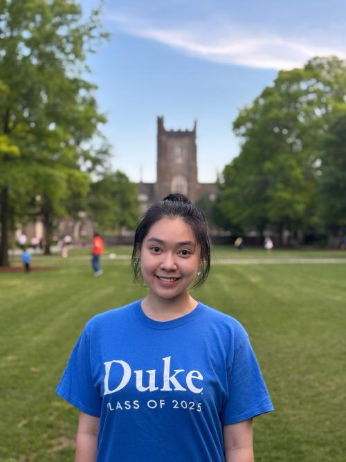 A person wearing a Duke t-shirt, standing on a grassy lawn on Duke's west campus