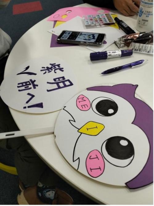 Fans on a table depicting an owl mascot and Japanese characters